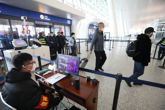 Staff members take passengers' body temperature at Tianhe International Airport in Wuhan, capital of central China's Hubei Province, Jan. 21, 2020. The Chinese city Wuhan has taken a string of measures to tighten the control and monitoring of outbound travelers in an effort to curb the spread of new coronavirus-related pneumonia. (Xinhua/Xiao Yijiu)